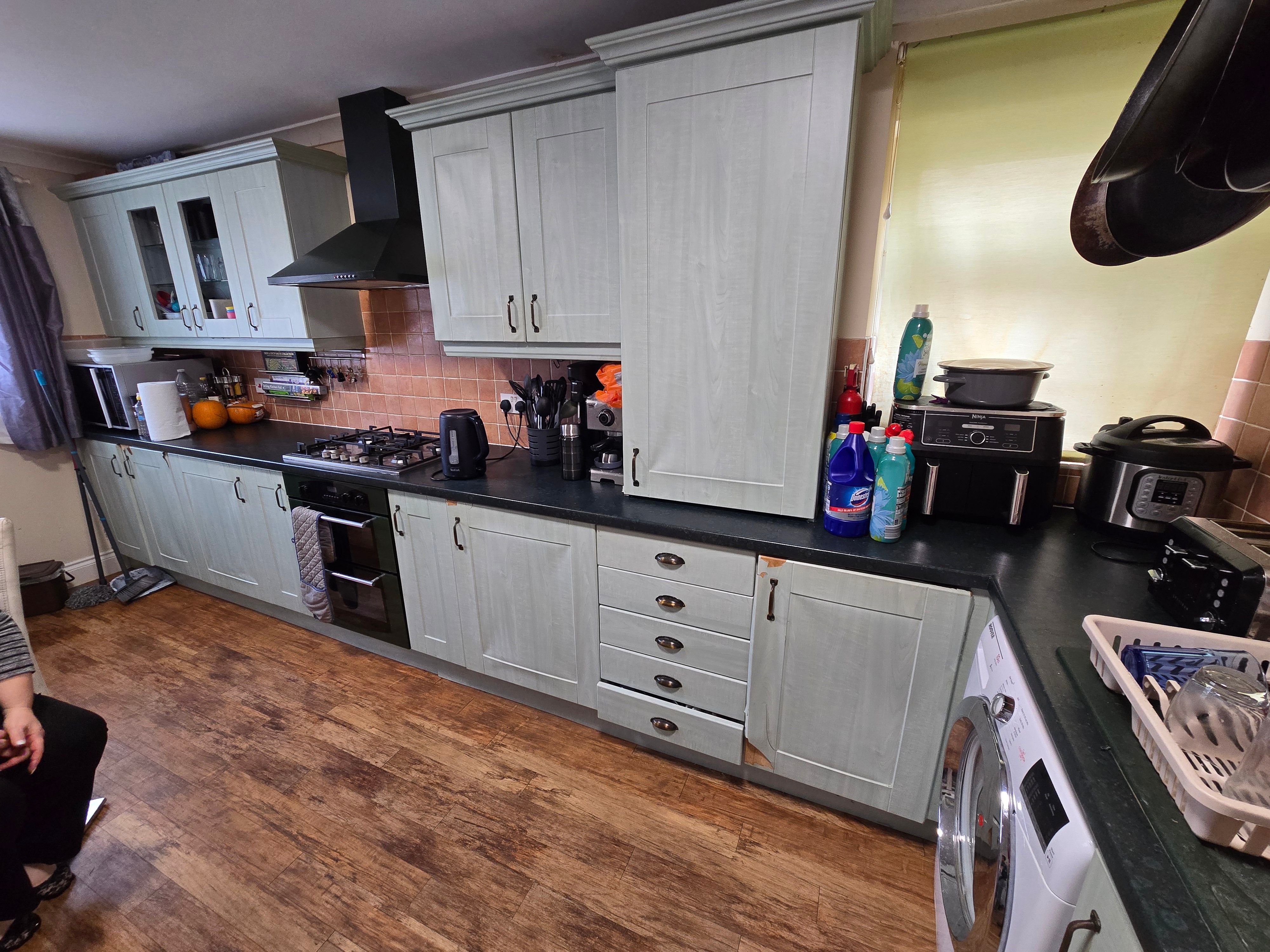 Kitchen before wrapping — grey/cream doors with visible damage, failing edges and exposed MDF