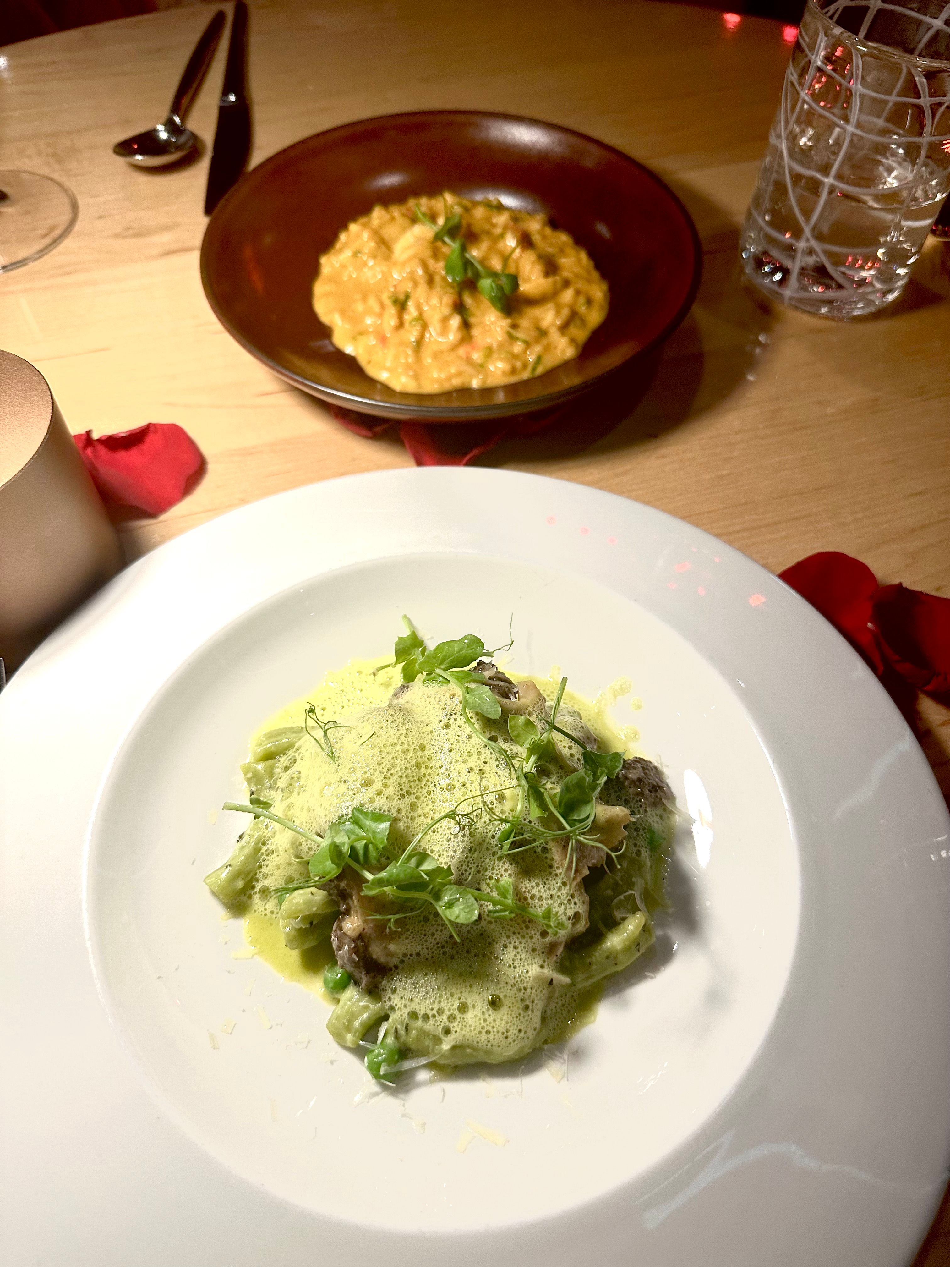 Marmalade tasting menu — two artfully plated dishes on a wooden table scattered with red rose petals, wine glass and candle in the background