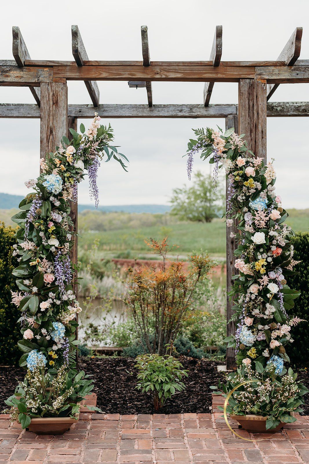 Wooden pergola with cascading floral installations at outdoor ceremony