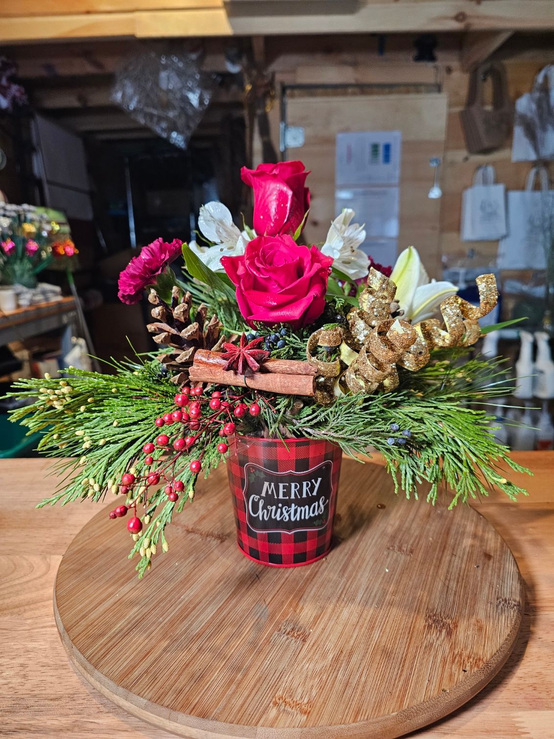 Merry Christmas arrangement with red roses, pine, and festive accents