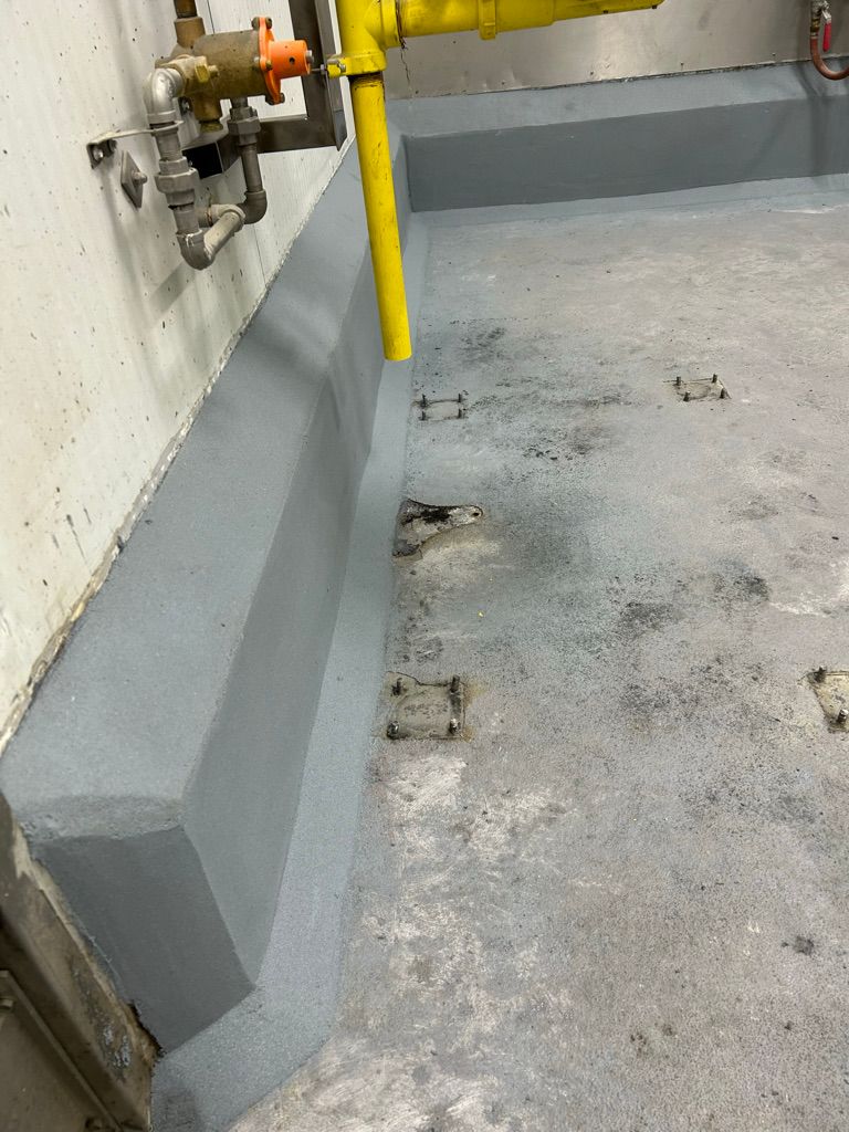 Restored floor corner with gray polymer base coat, metal anchor brackets, utility pipe and yellow gas line