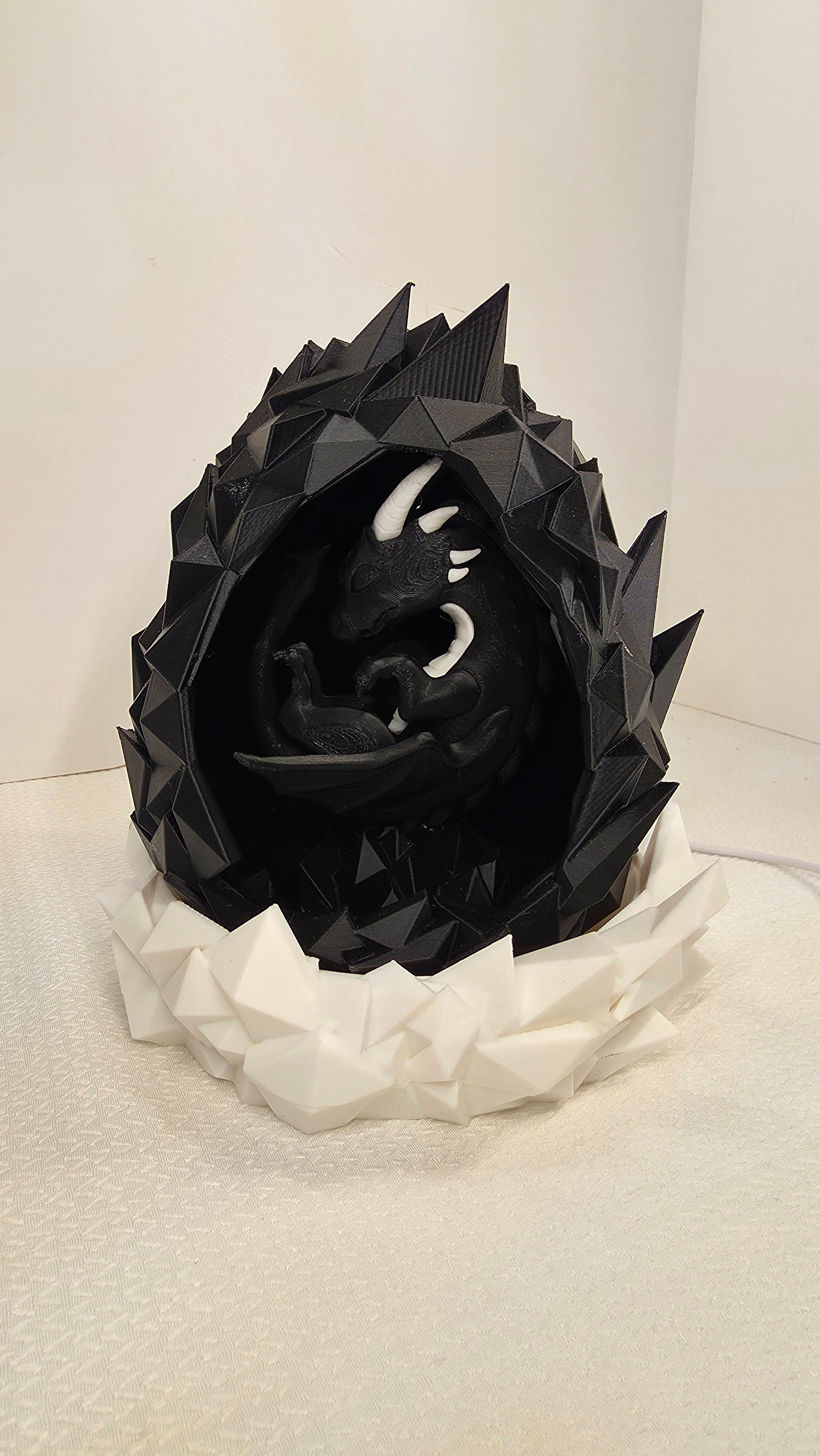 Black dragon in geometric spiked egg with white base
