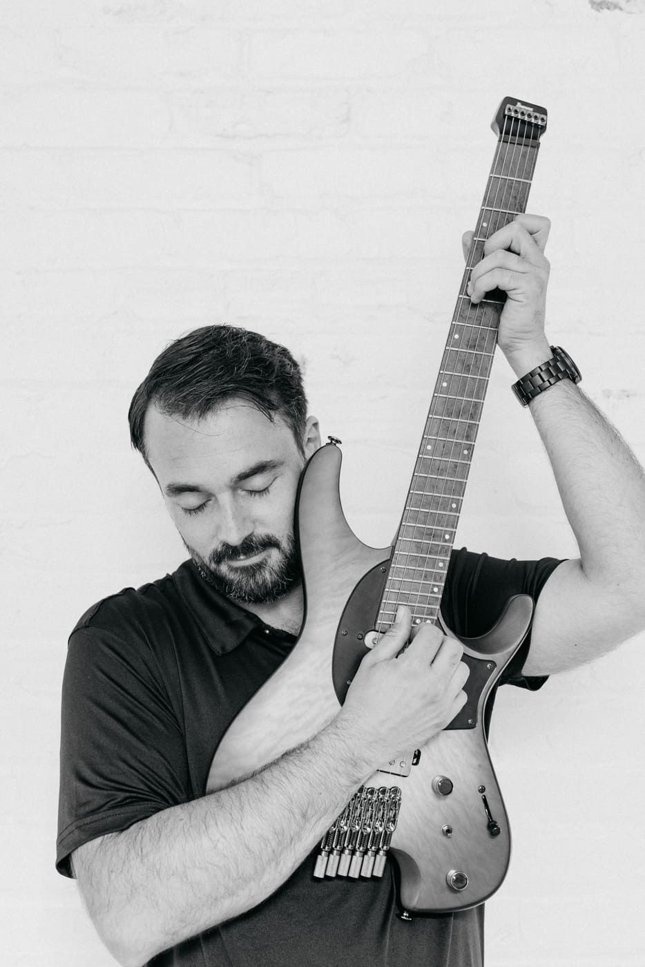 Tyler holding a guitar close with eyes closed — the personal connection between a musician and their instrument
