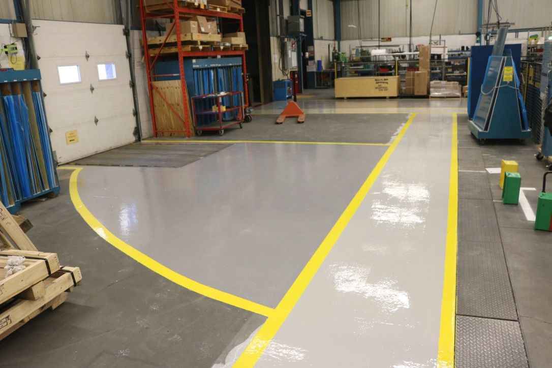 Industrial warehouse with polished epoxy floor marked by yellow Lean 5S pathway lines and pallet jack