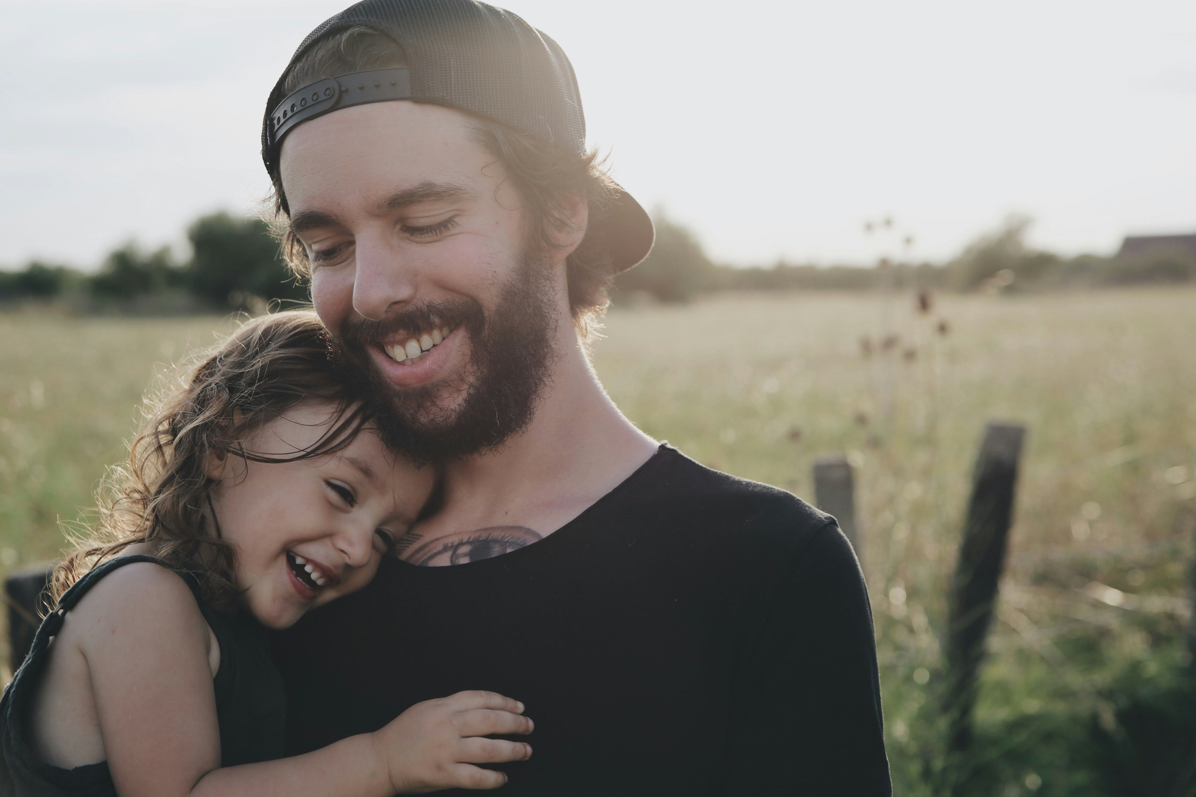 Father in a field holding his laughing daughter