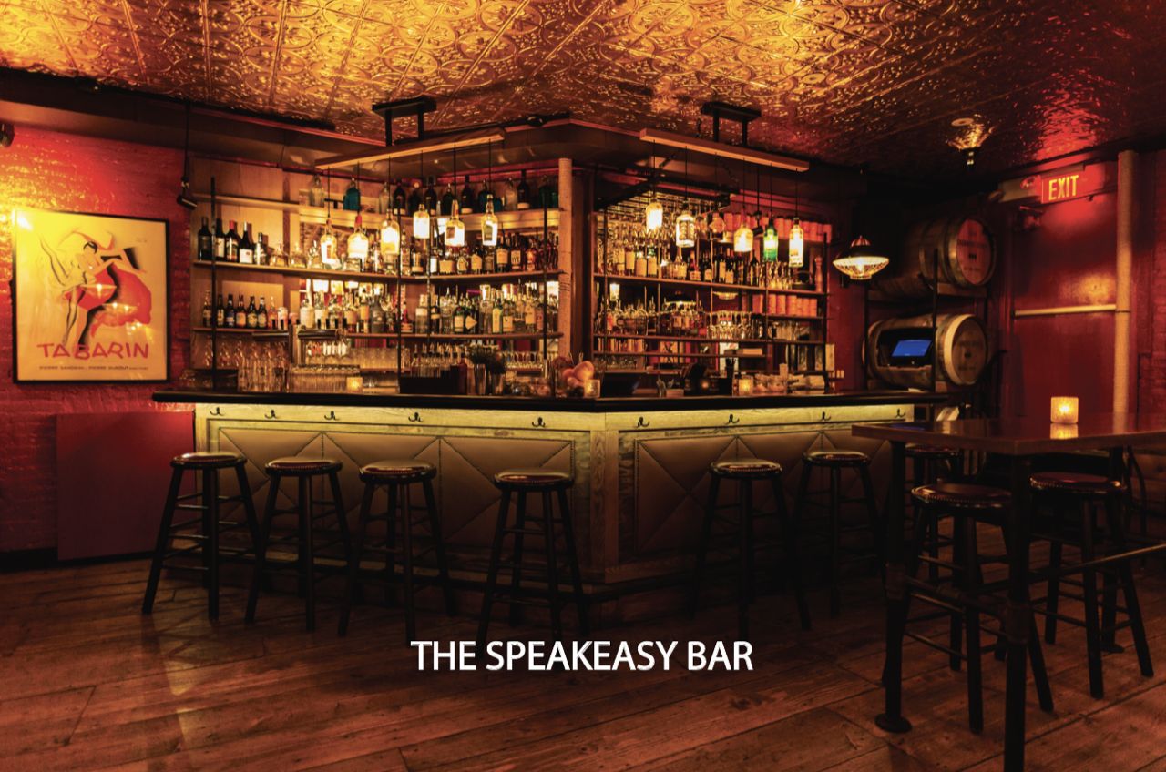 Furtivo Speakeasy interior — dimly lit bar with red walls, ornate ceiling, shelves of bottles, and warm amber lighting