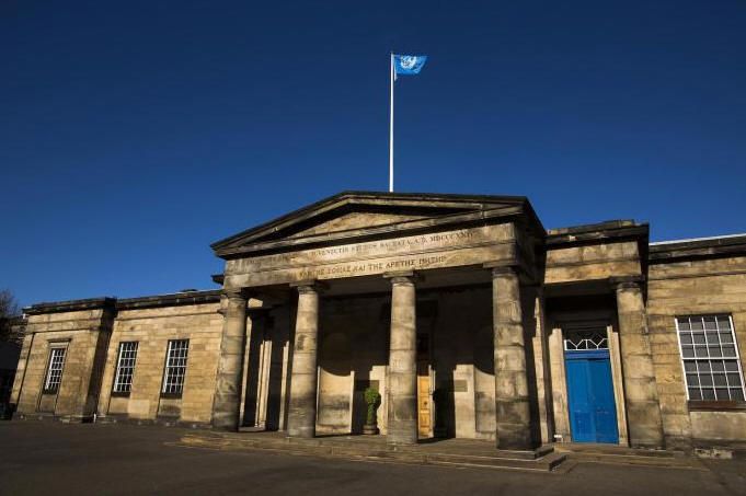 Edinburgh Academy building with flag flying above the neoclassical stone facade at sunset