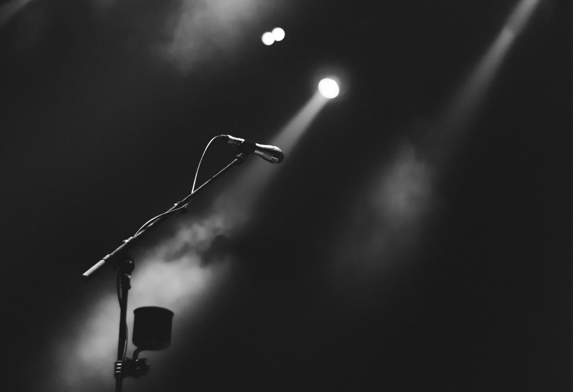 Dramatic black and white microphone on stand with spotlights and stage smoke