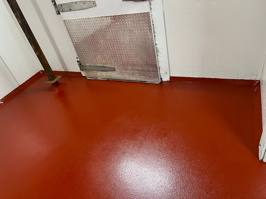 Seamless reddish-brown epoxy floor corner with diamond-plate door in food facility