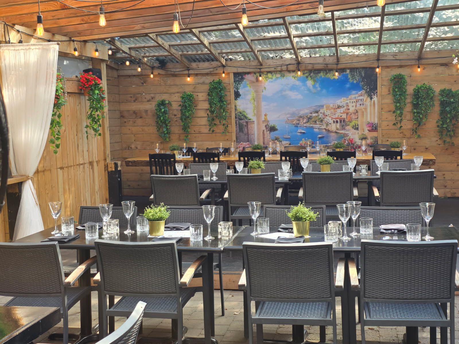 Olio patio with Mediterranean mural, string lights, and tables set for a wedding celebration