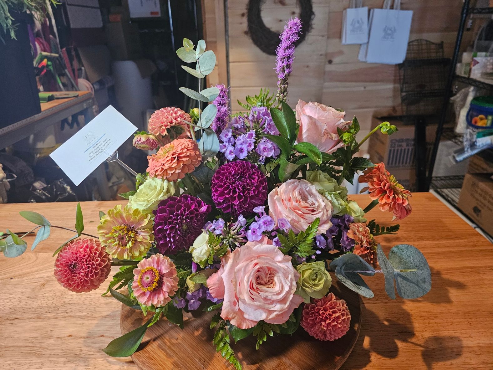 Colorful summer arrangement with pink roses, zinnias, and eucalyptus