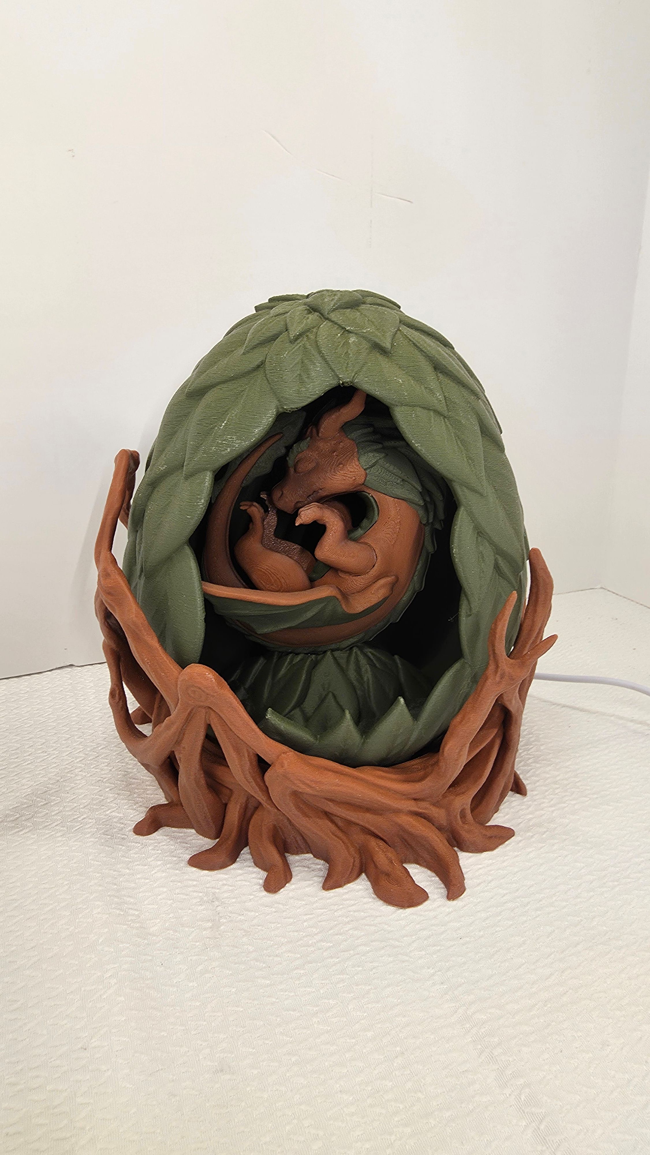 Brown dragon sleeping in green leaf egg sculpture