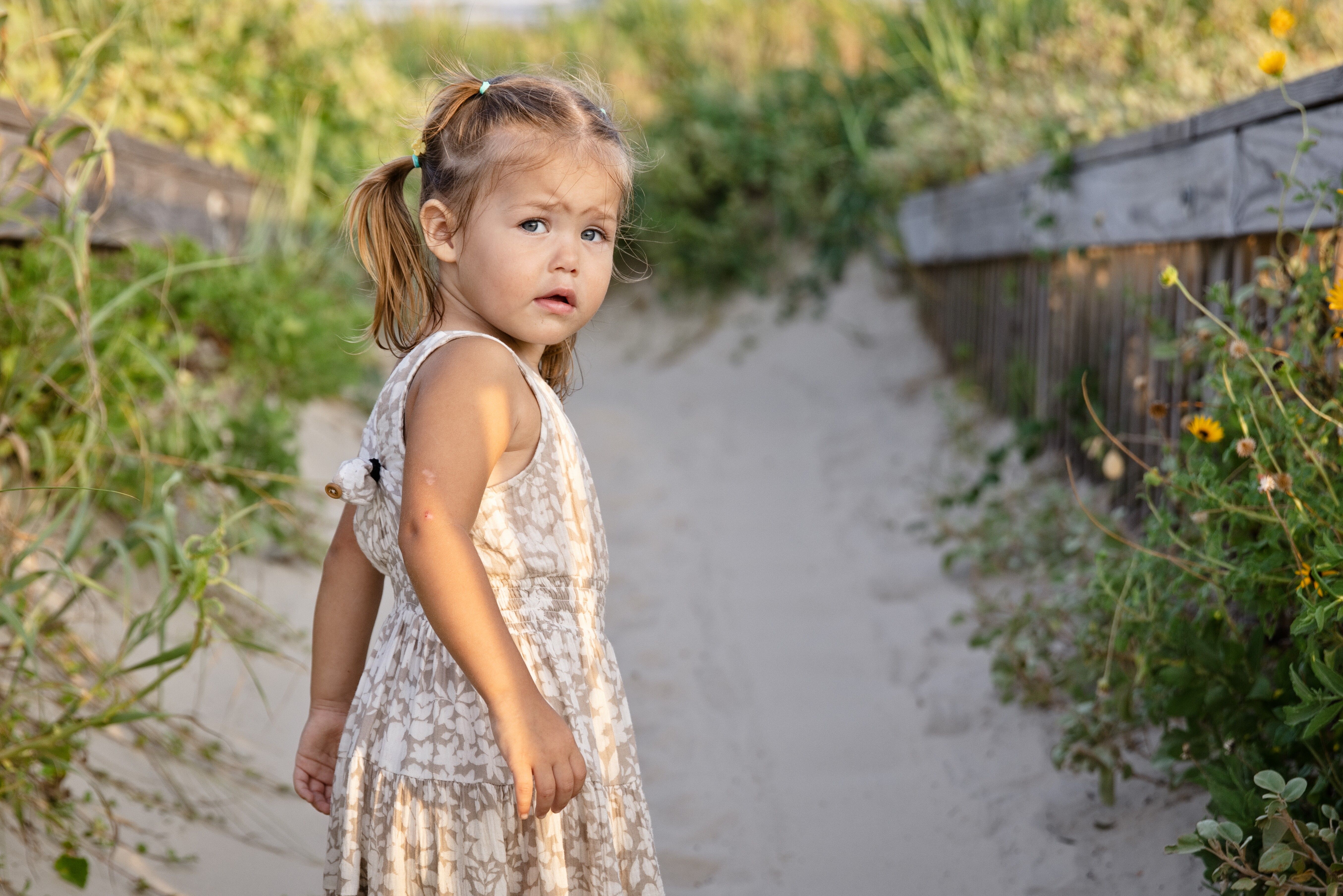 Little girl on a flowery path leading to the beach