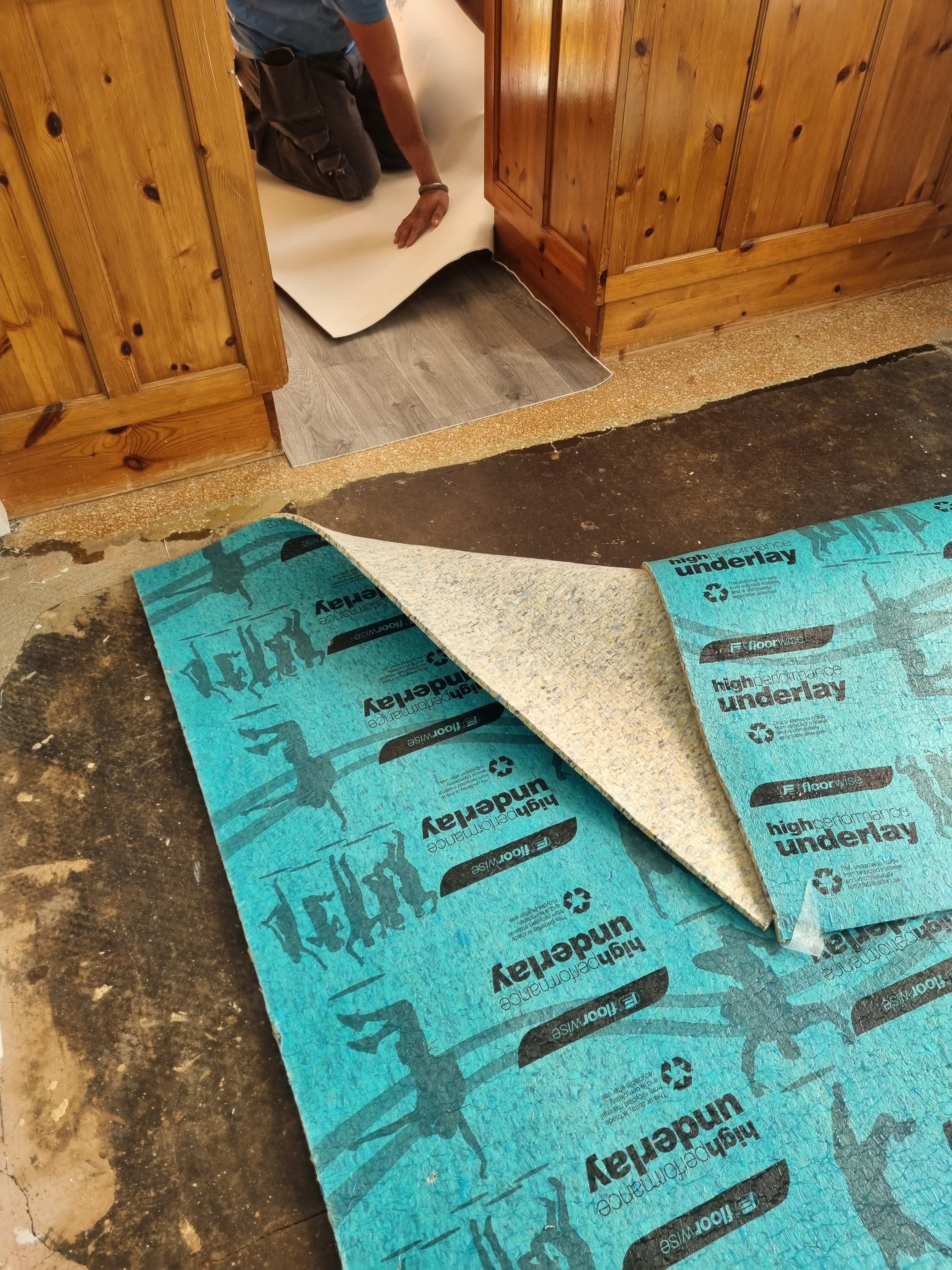 Technician laying laminate flooring with underlay