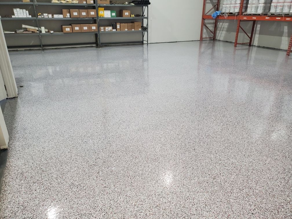 Warehouse storage room with shiny speckled epoxy floor and organized metal shelving with supplies