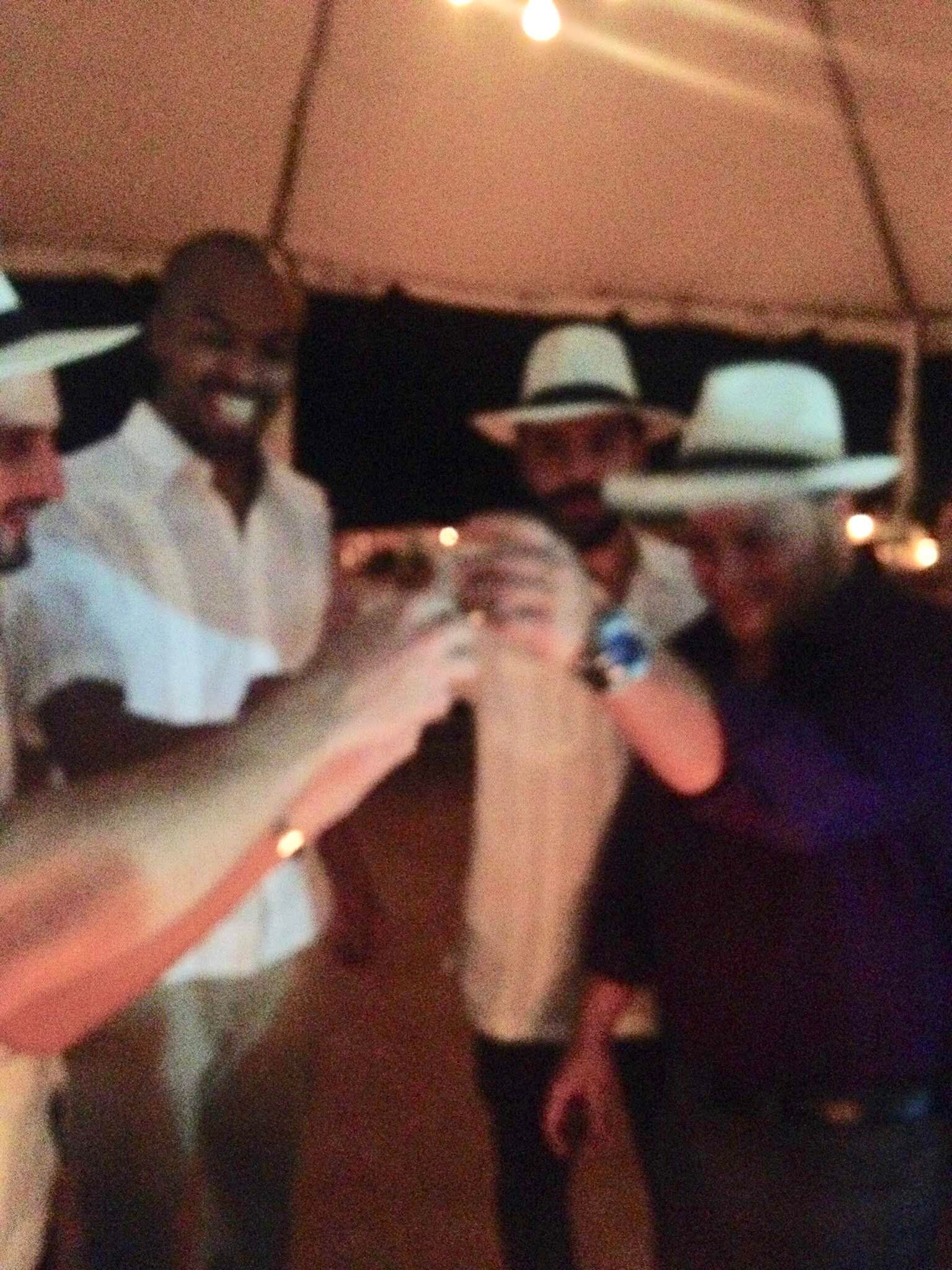 Group of friends in Panama hats raising glasses in a toast — Latin Vibes energy