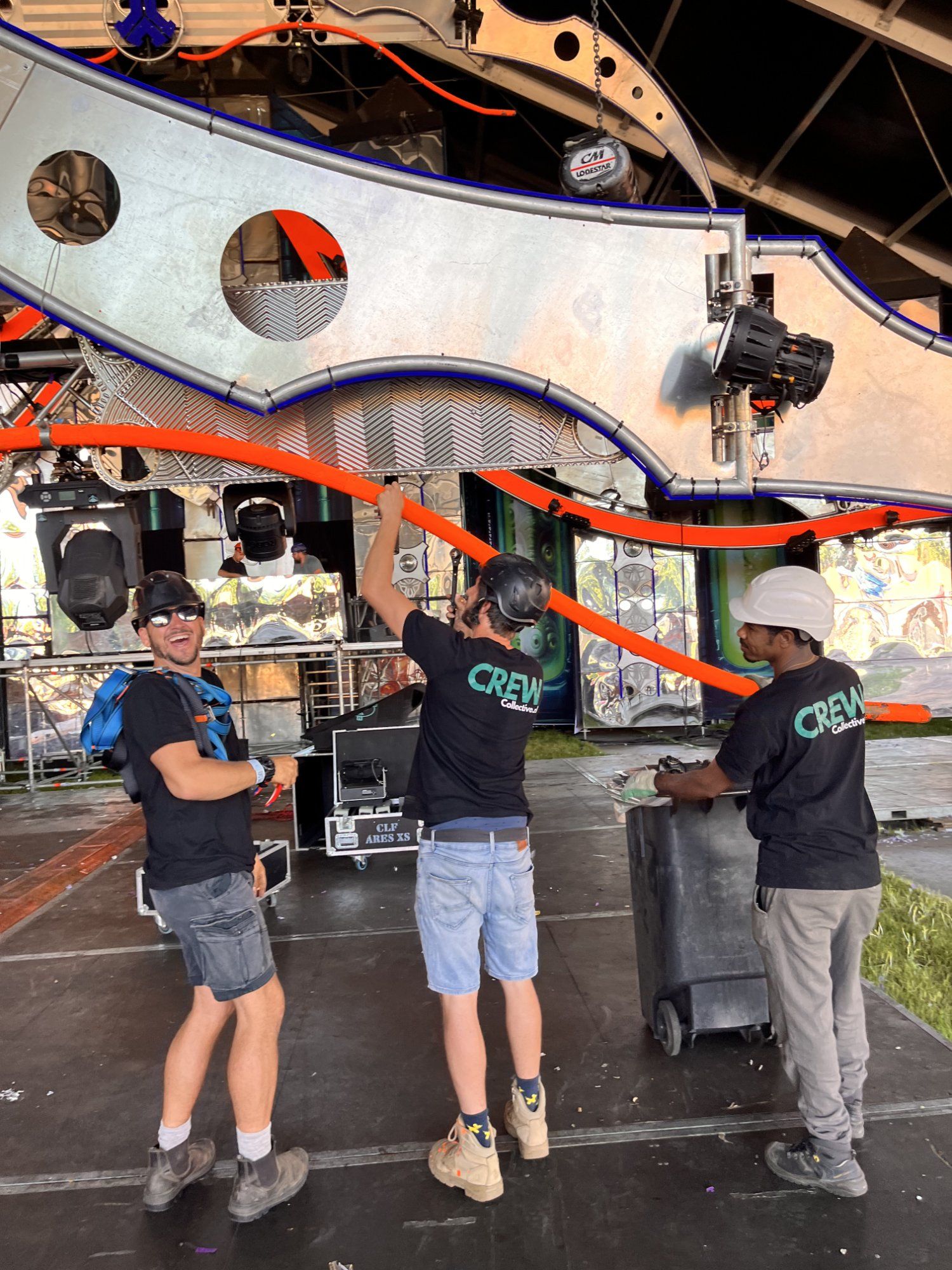 Stagehands tillen samen een groot decorstuk op een podium tijdens de opbouw van een evenement