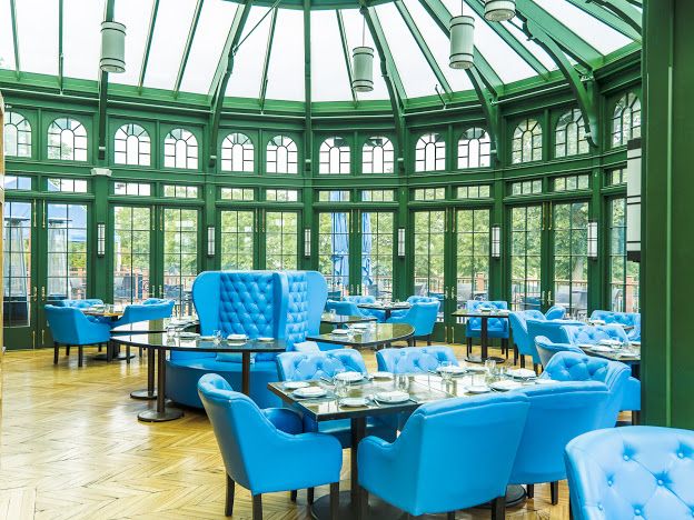 A bright dining room with blue seating and green-framed windows