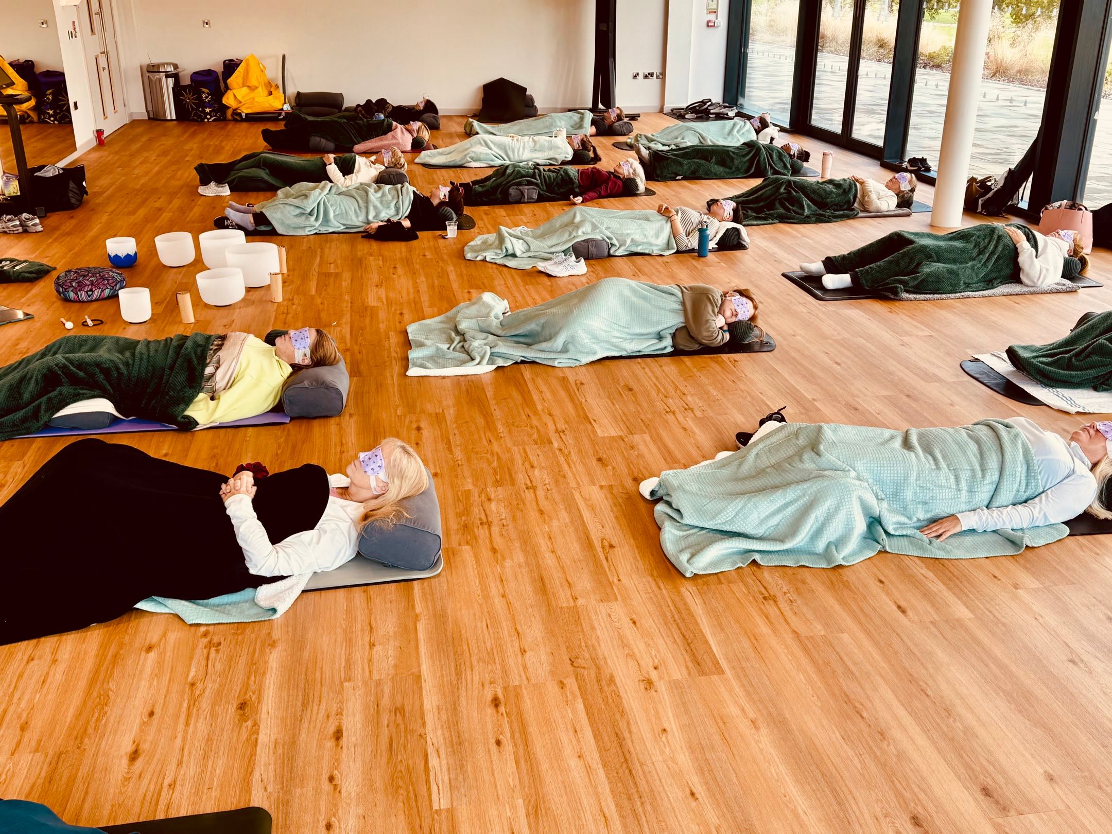 A group resting on mats with blankets in The Stillpoint class at The Belfry