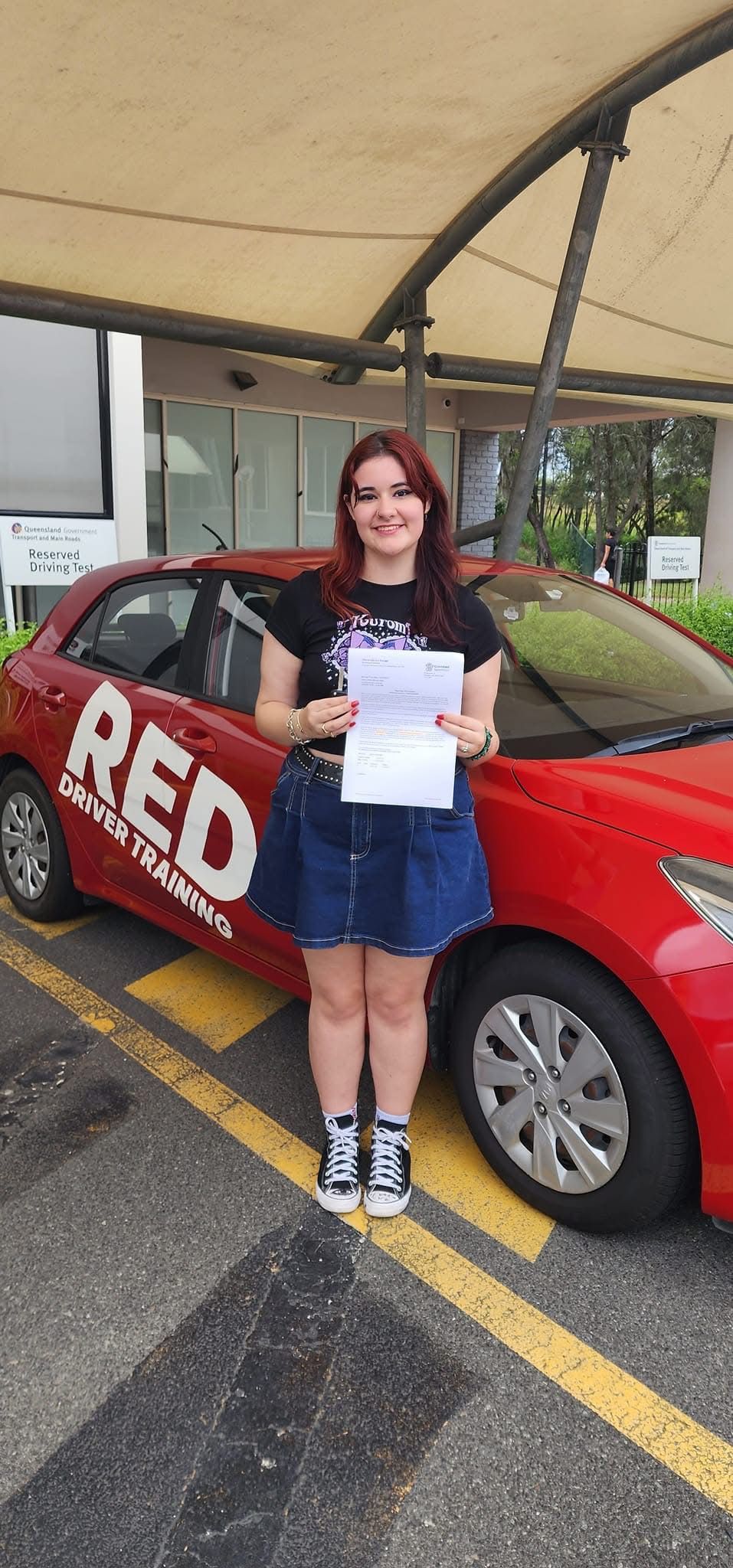 Noah proudly holding P plates after passing her practical driving test at Helensvale test centre