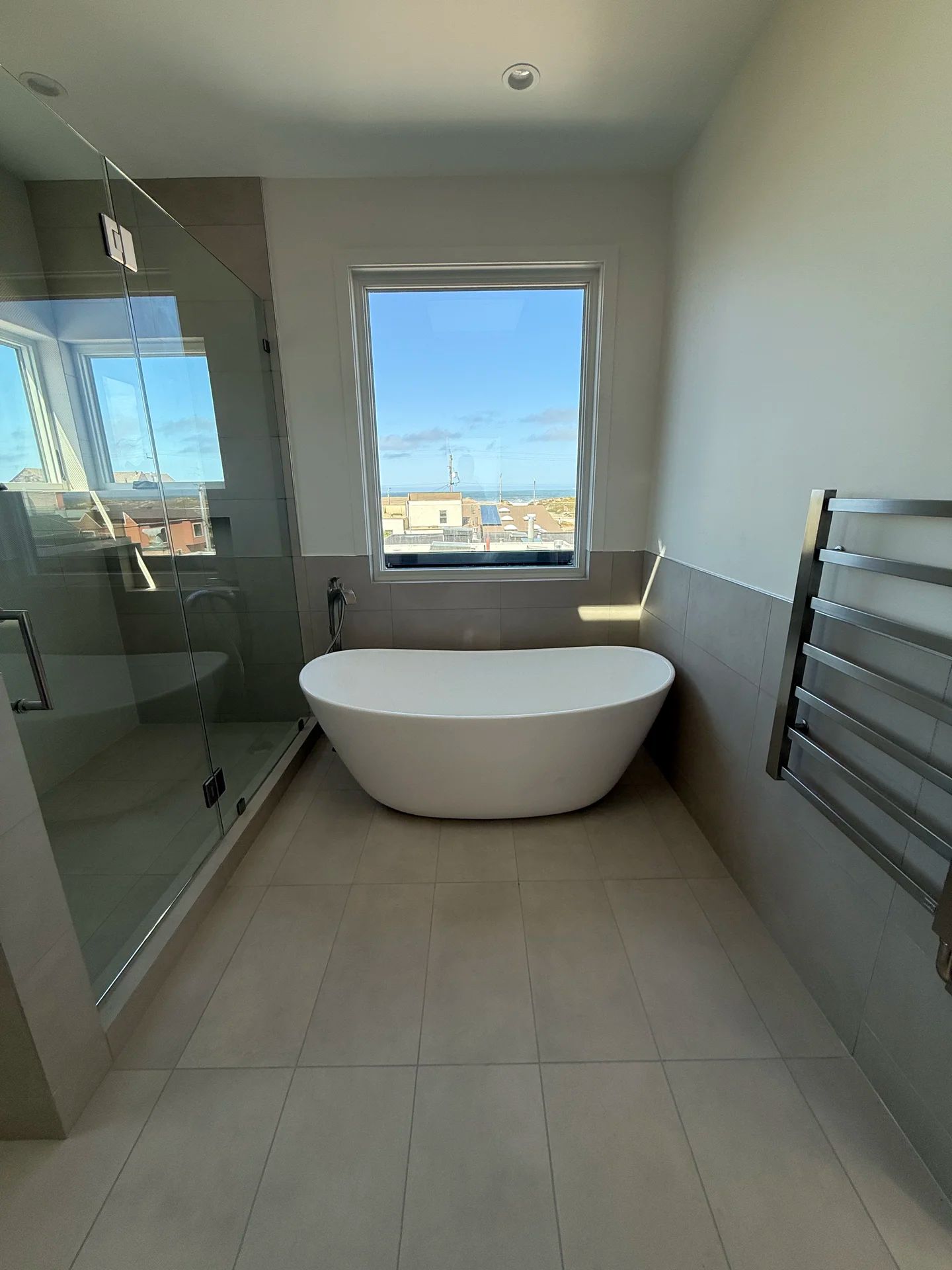 Freestanding bathtub with city view — luxury bathroom by PGKB San Francisco