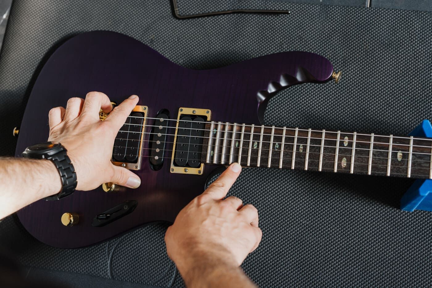 Close-up of a purple electric guitar being inspected during repair