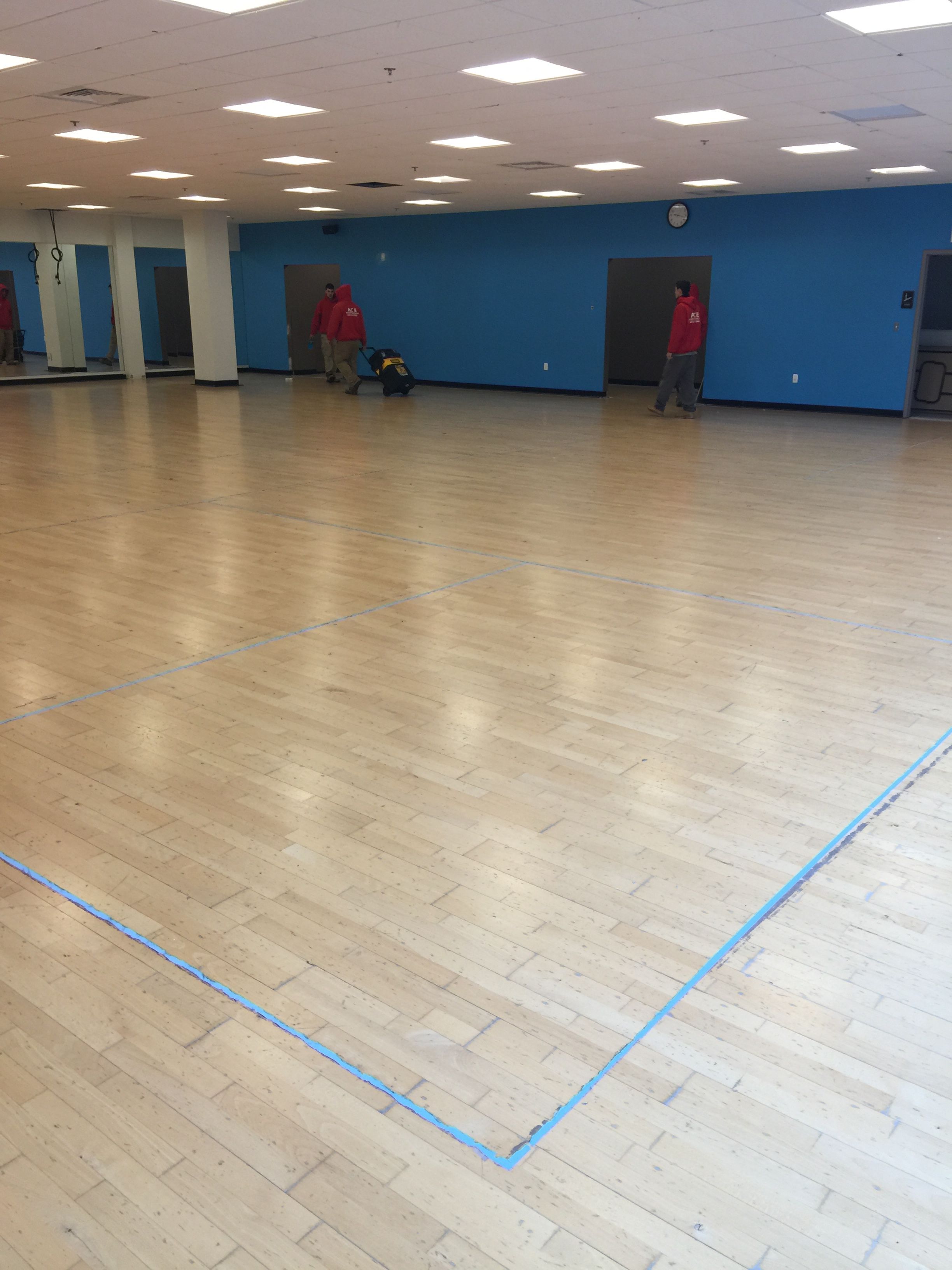 IWF crew sanding commercial gym maple hardwood floor — team at work mid-project
