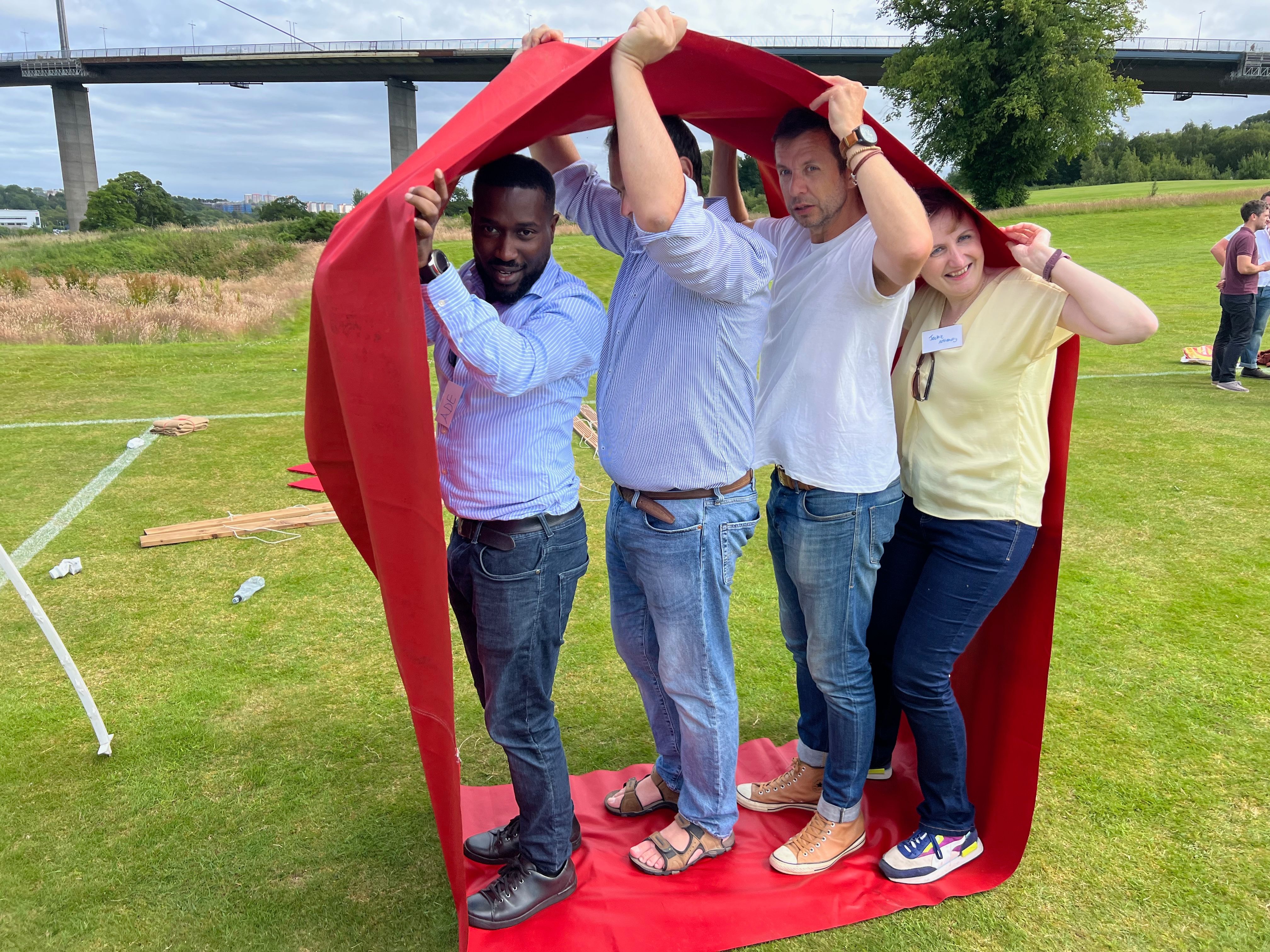 Four teammates navigating a red looped mat challenge during It's a Knockout team building event