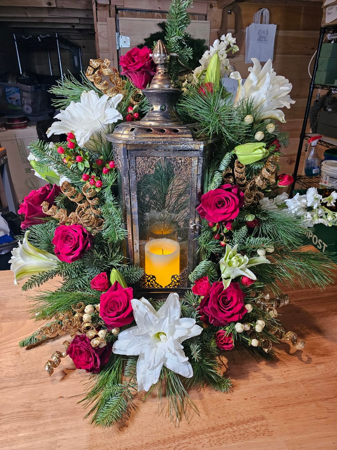 Holiday lantern arrangement with roses, pine, and cinnamon accents