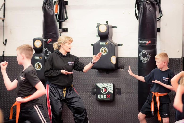 Instructor training with two young students in orange belts