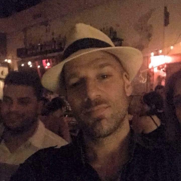 Xavier in a fedora hat at a bar — the host of Latin Vibes