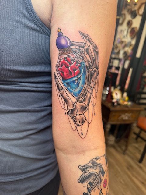 Color tattoo by Justin - skeletal hand holding a bottle with a heart inside