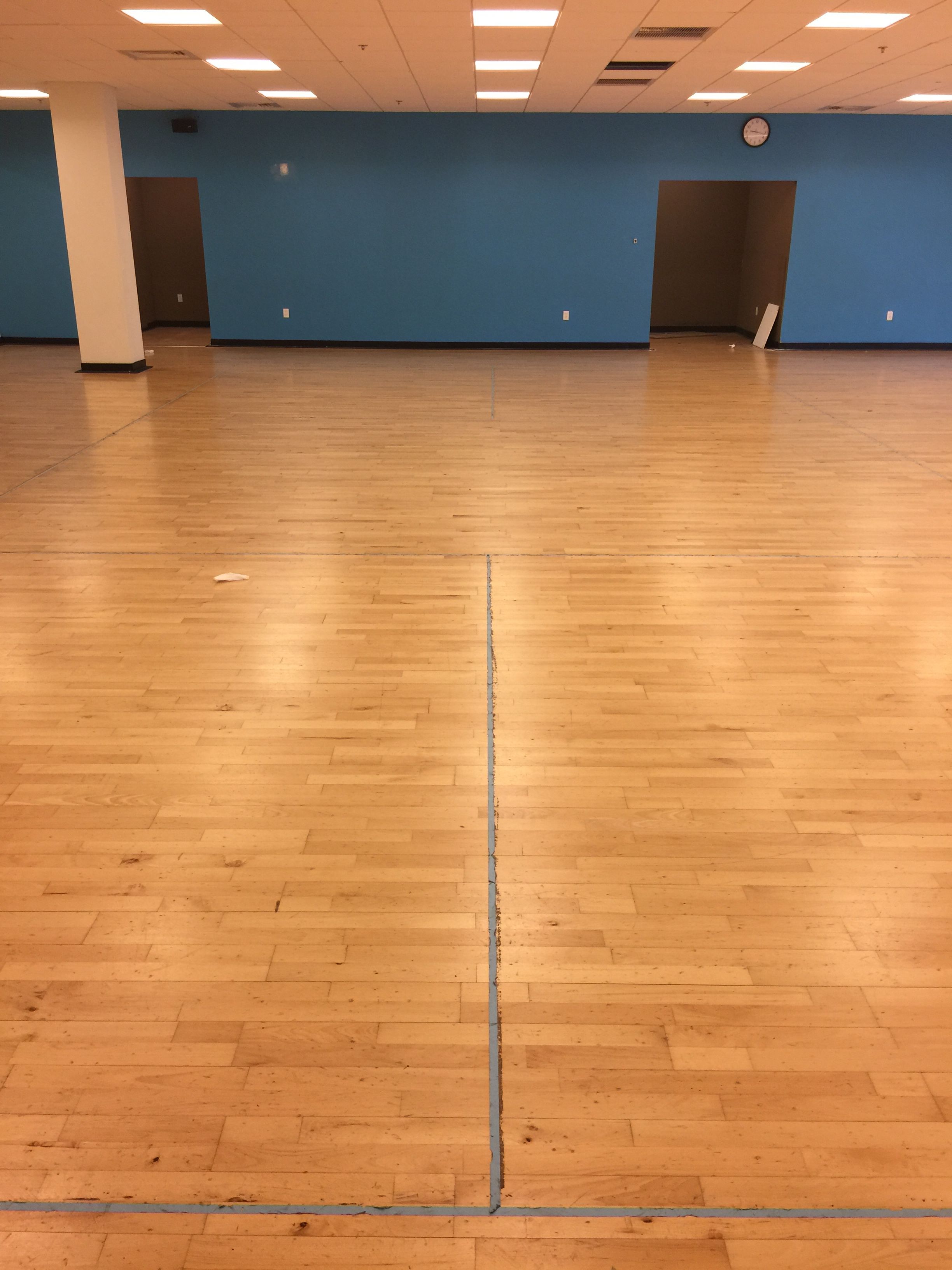 Commercial gym maple hardwood floor before refinishing — worn court with faded lines