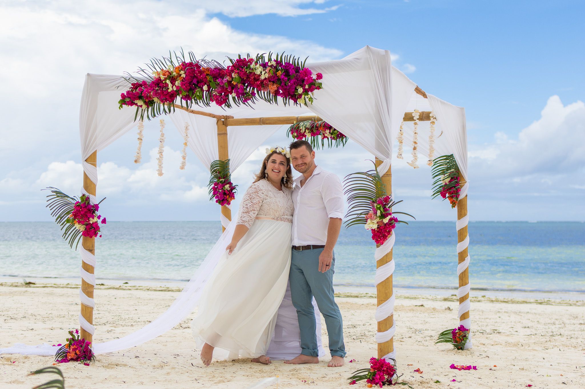 Couple under floral arch on beach with ocean backdrop