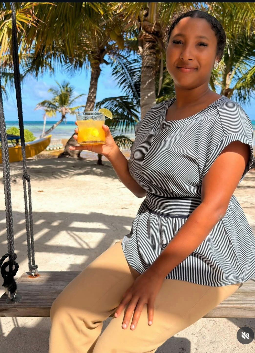 Woman on beachfront swing with tropical cocktail at Infinity Island, San Pedro Belize