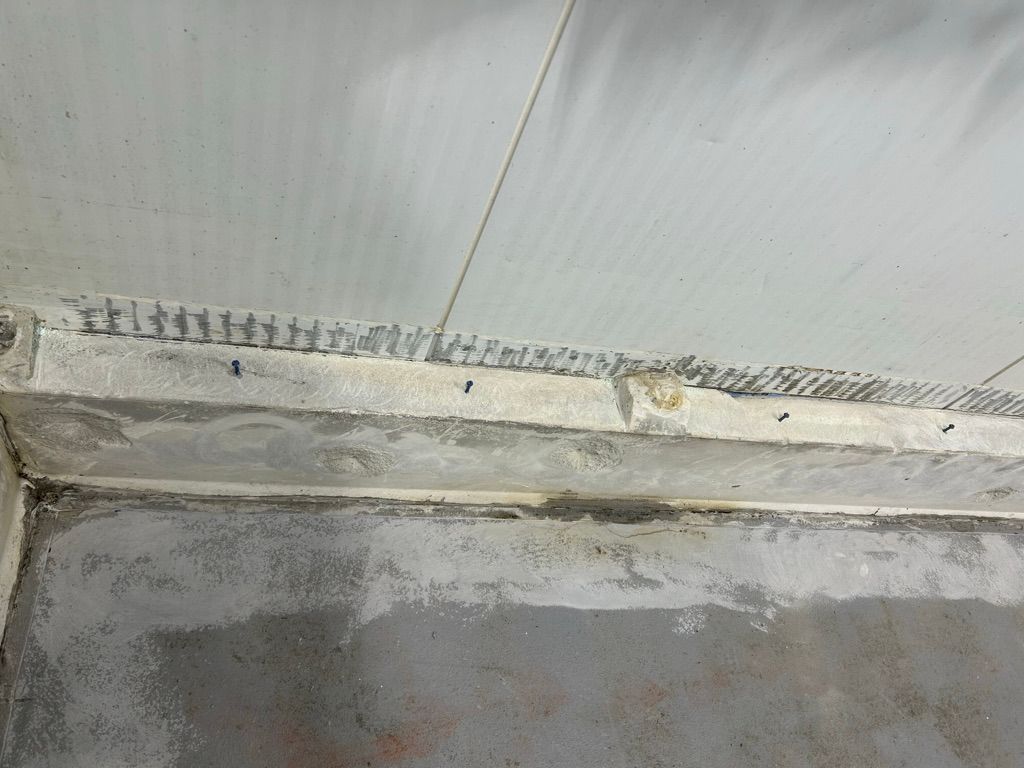 Wall-to-ceiling junction with rough surface texture and cove base strip installation in progress