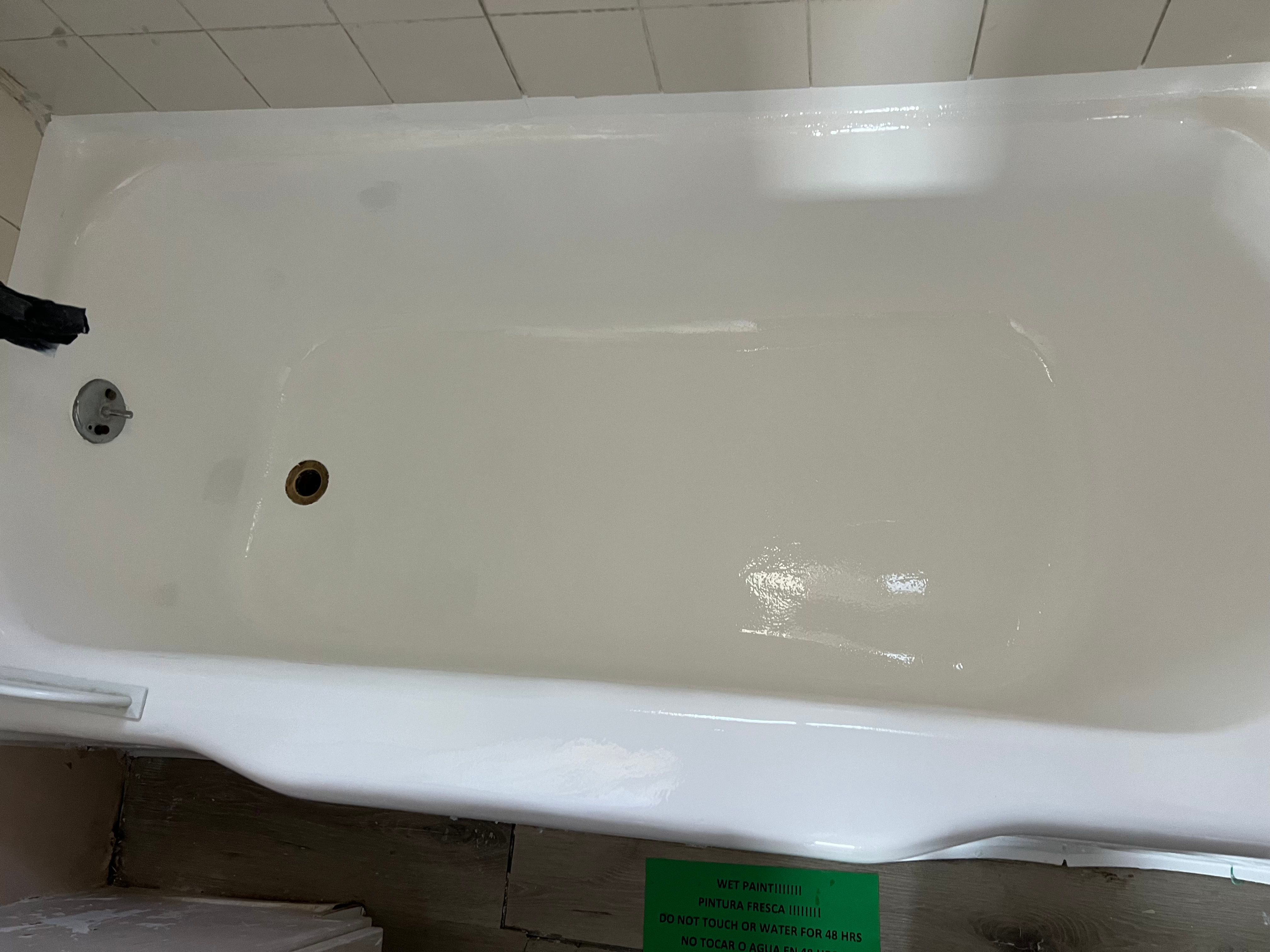Bathtub after reglazing — clean white finish with wet paint sign by PMR Projects