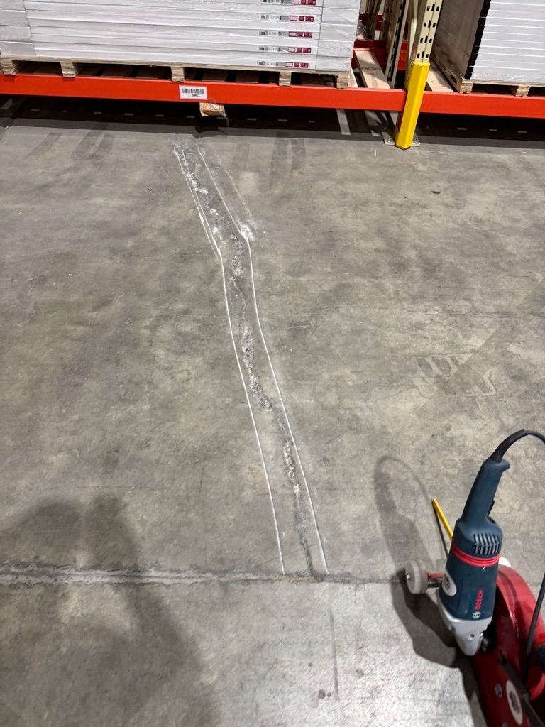 Concrete cutting and crack routing in a warehouse aisle during floor preparation for epoxy application