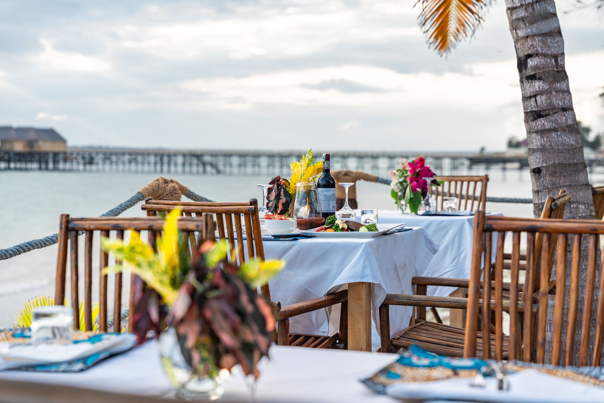 Seaside dining setup with wine and flowers at Zanzibar hotel β hospitality photography