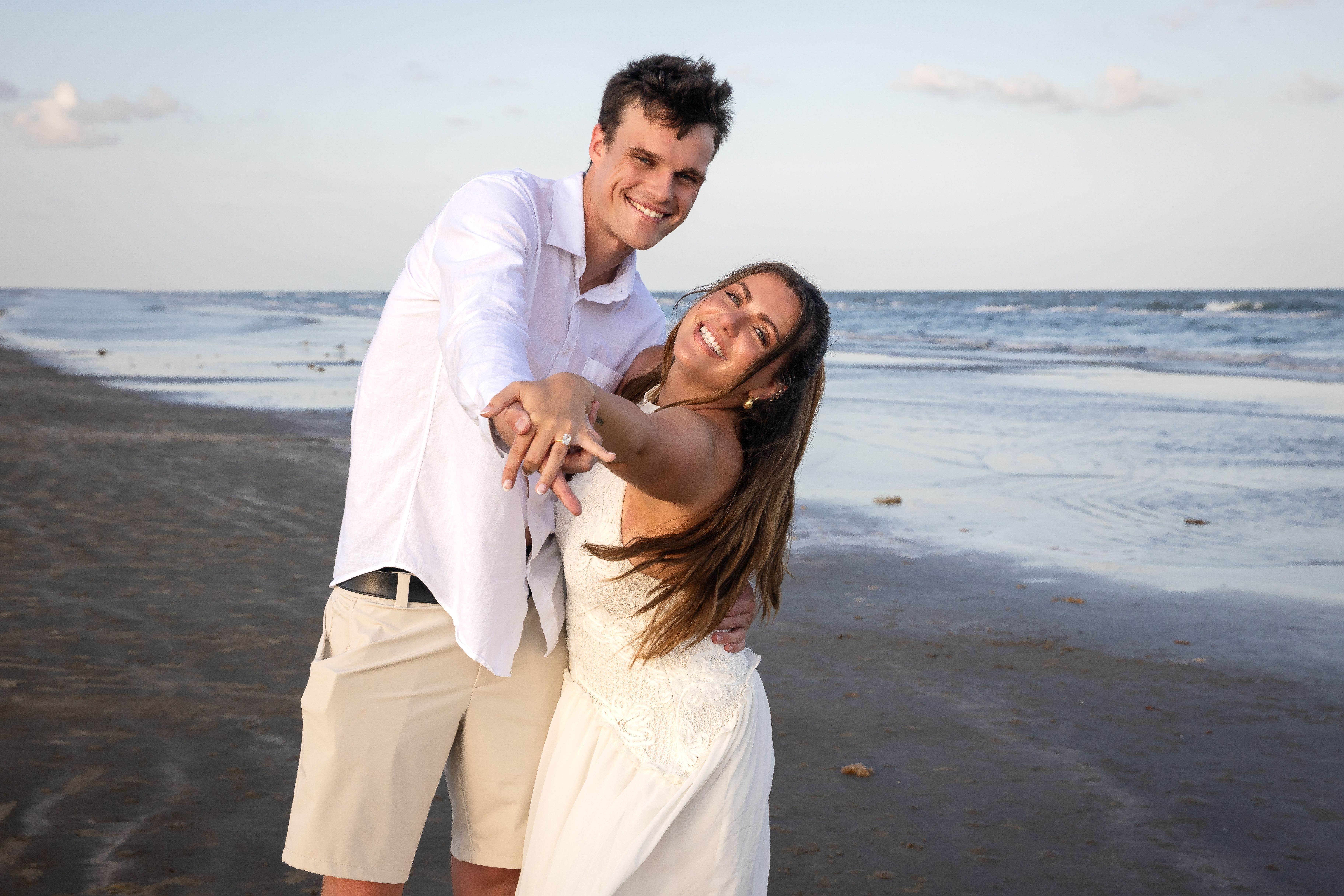 Couple showing off engagement ring on the beach