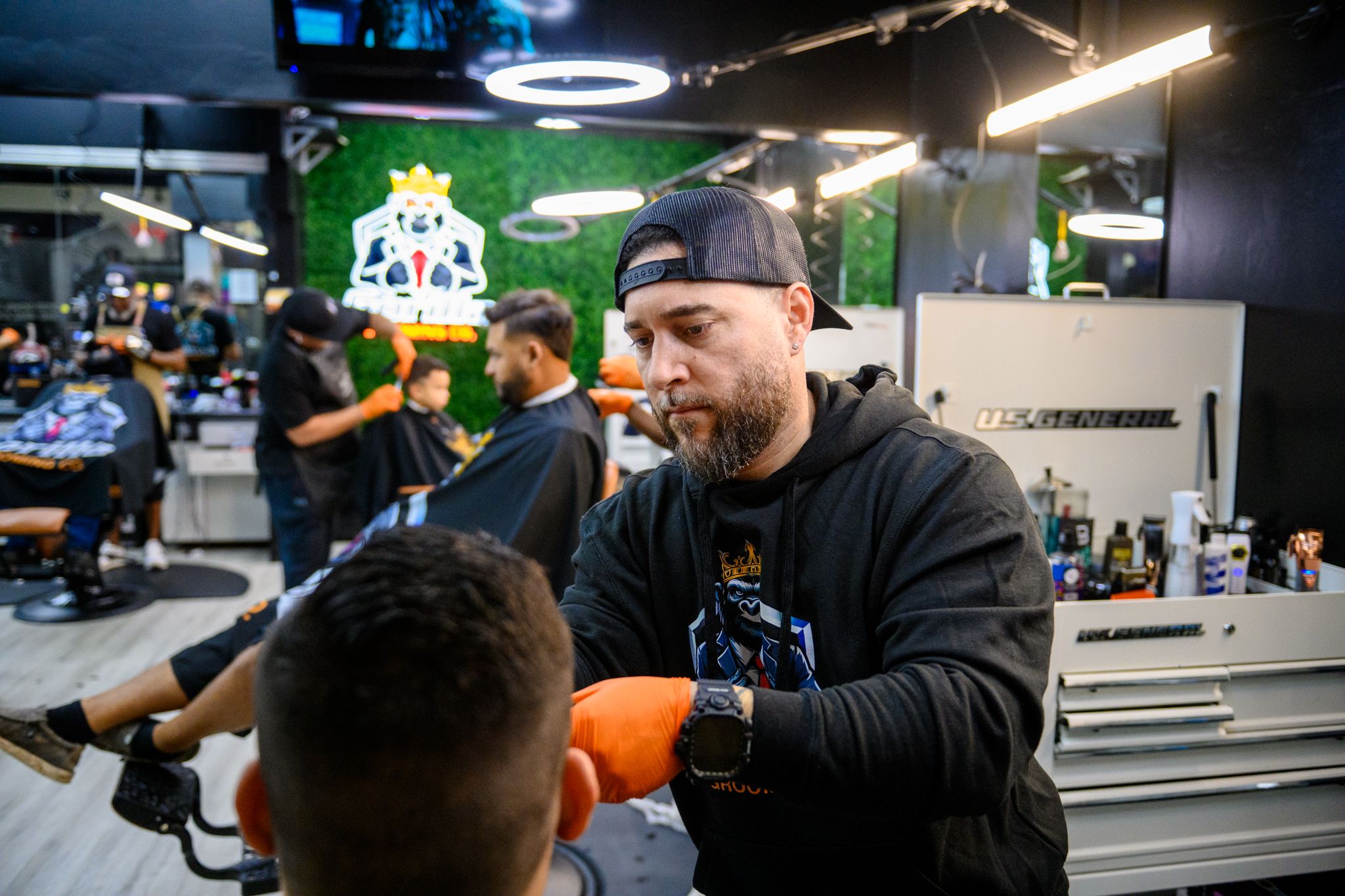 Barber focused on precision fade with orange gloves and clippers