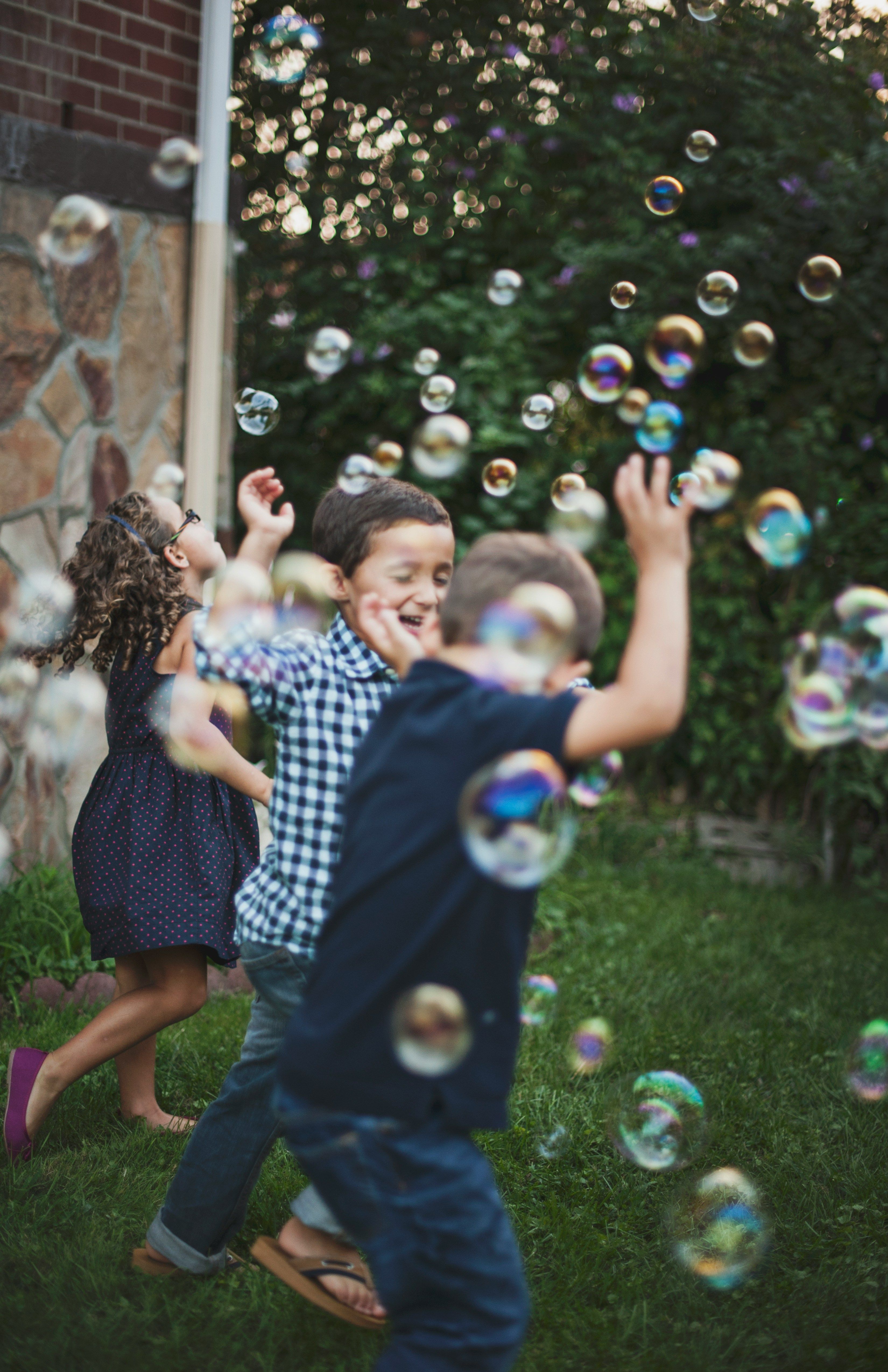 Children playing outdoors chasing bubbles
