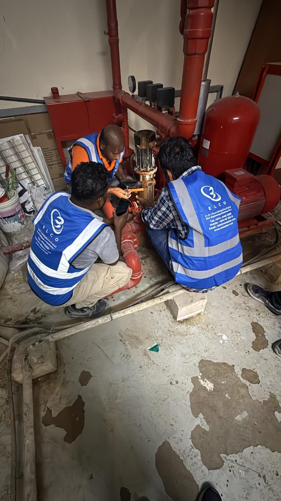 ELCO team in branded blue vests working on red industrial pipes and machinery