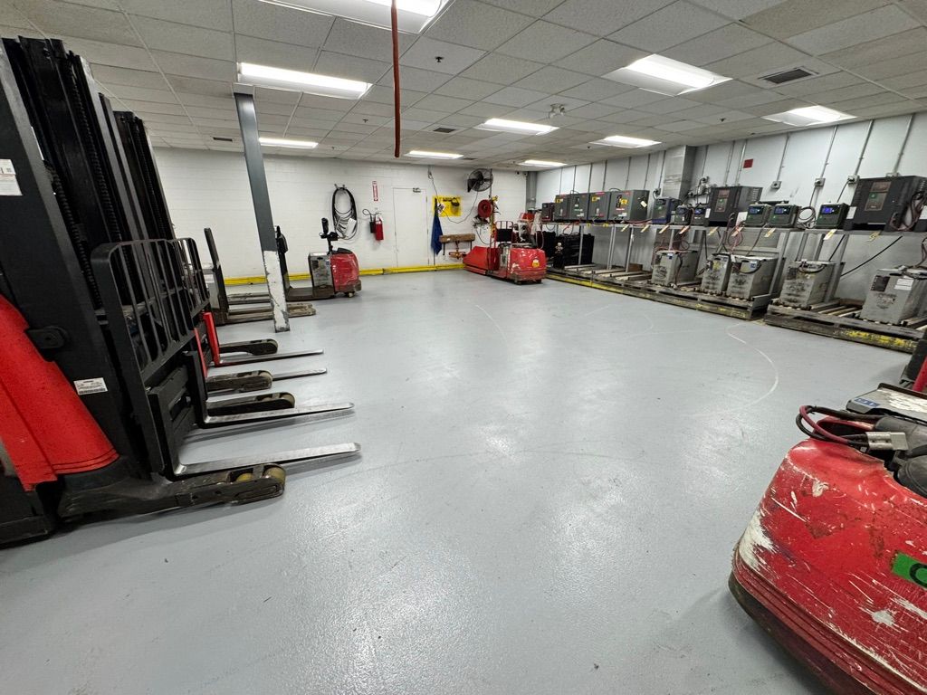 Manufacturing facility forklift charging room with smooth grey epoxy floor and battery charging stations