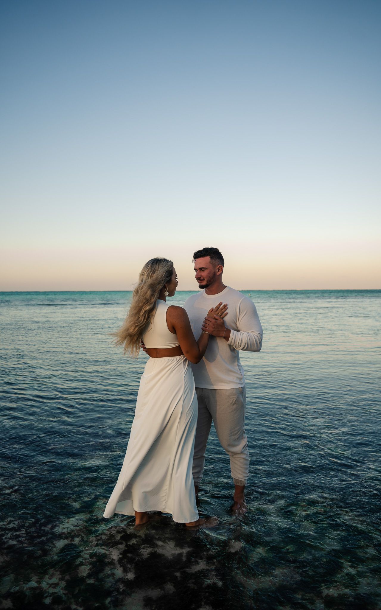 Romantic couple holding hands in shallow water at sunset — classic beach photography Zanzibar