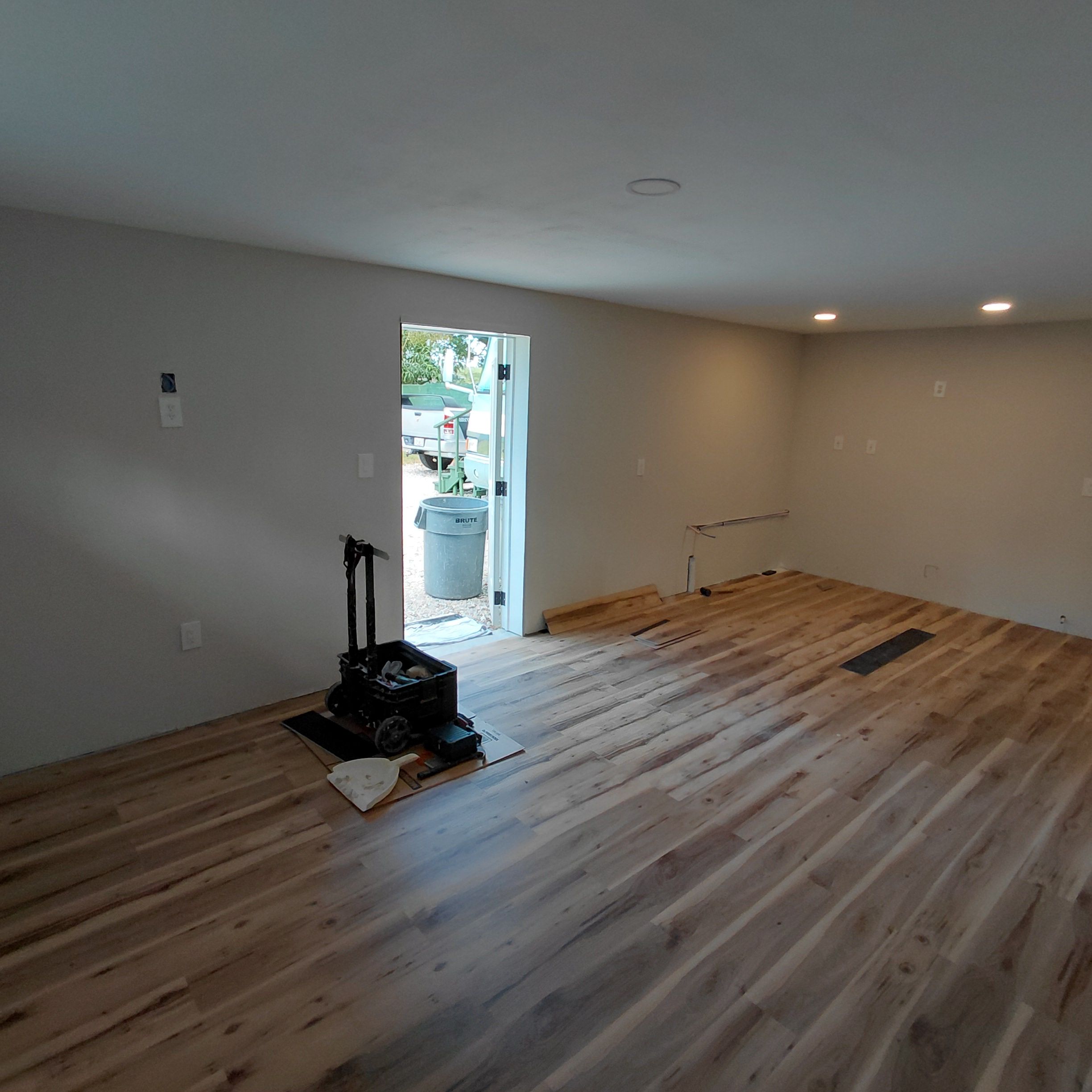 Finished room with new flooring and tools staged near the door