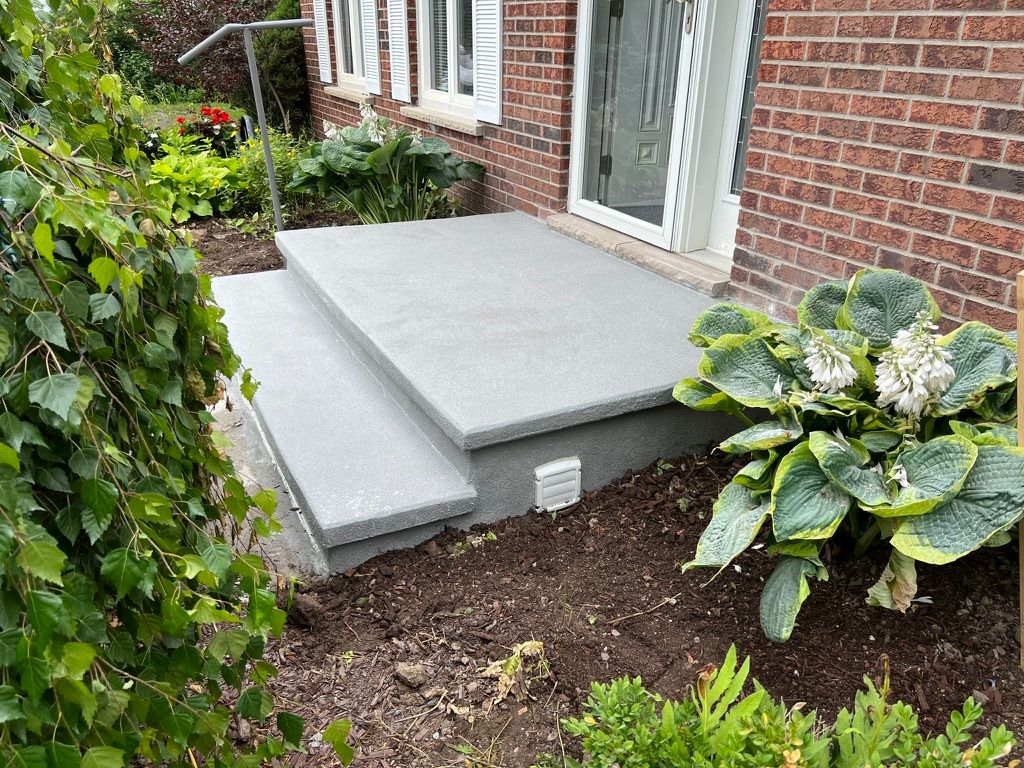 Small residential concrete porch before restoration — brick house with white vent and garden surround