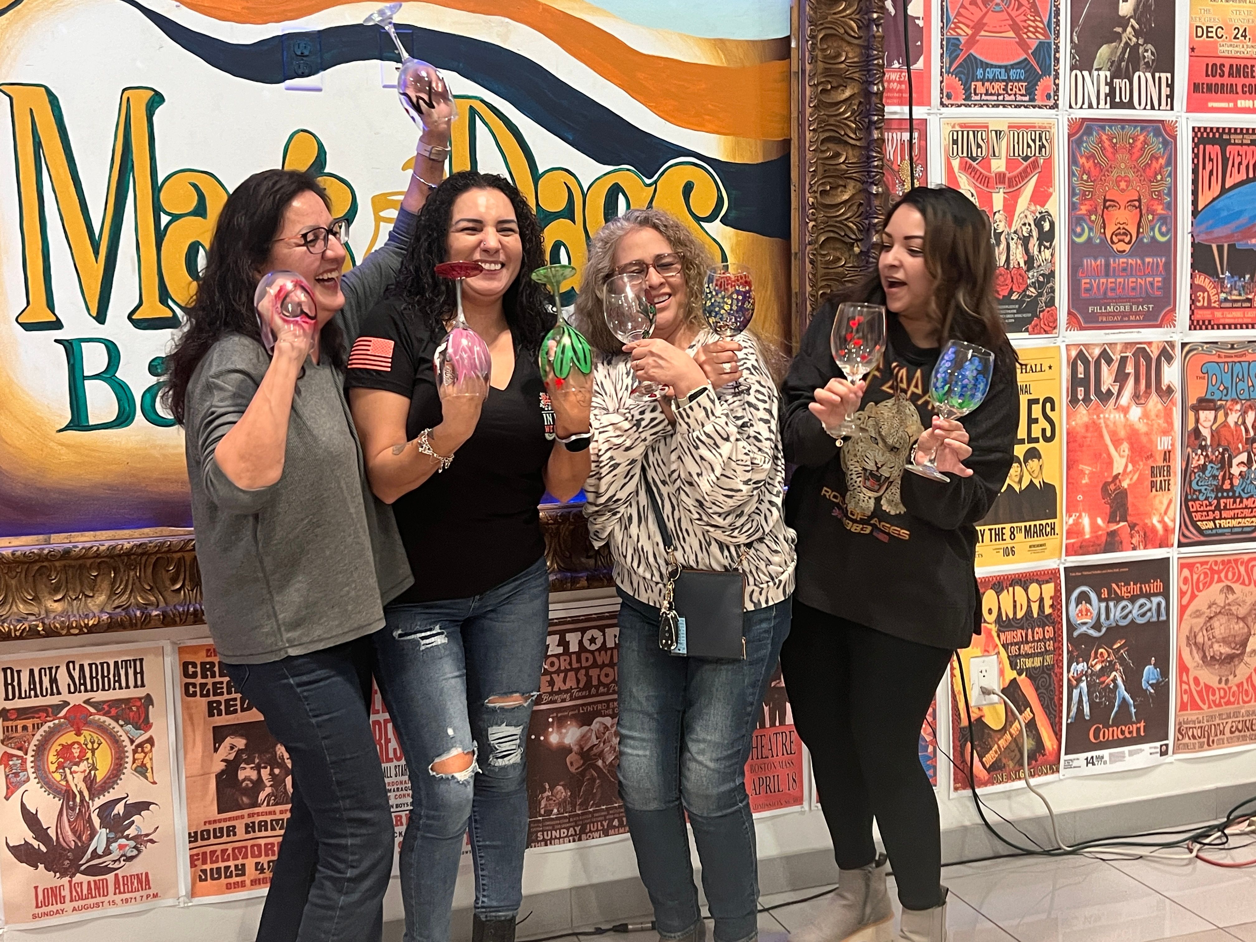 Four women showing their painted wine glasses at craft party