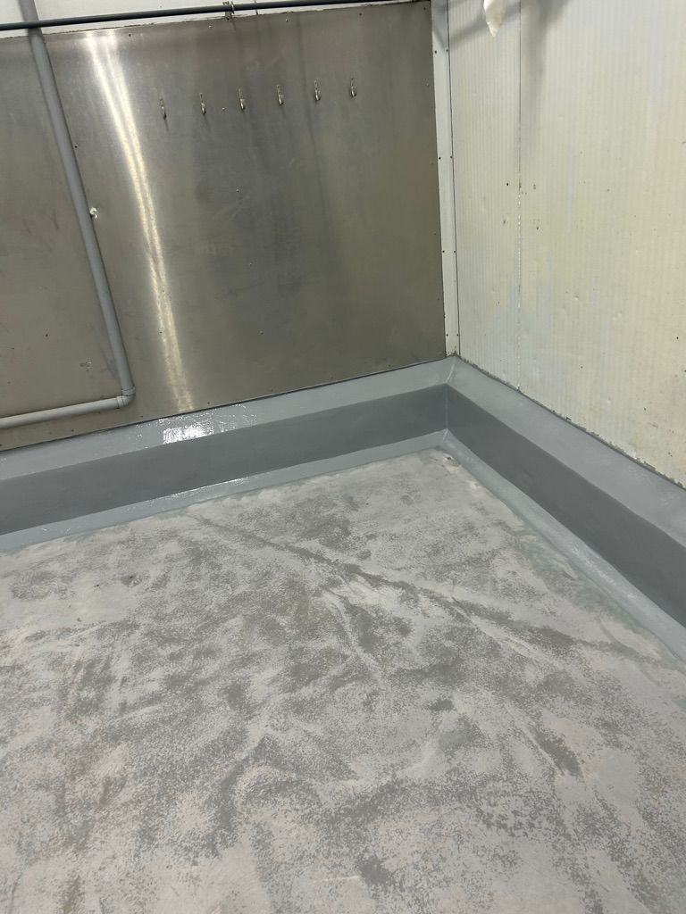 Corner of commercial facility with metallic wall panel, hooks and textured cove base floor transition in progress