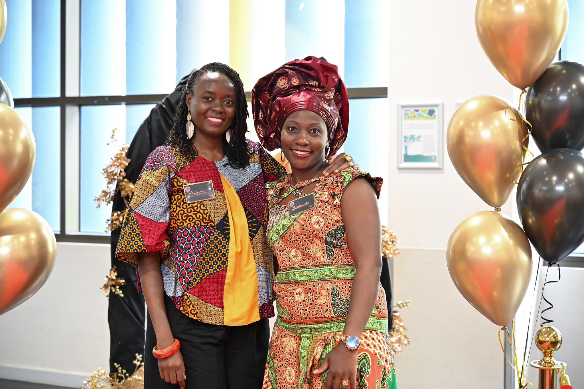 Two women in beautiful traditional African attire smiling at E-Girl Empowerment event